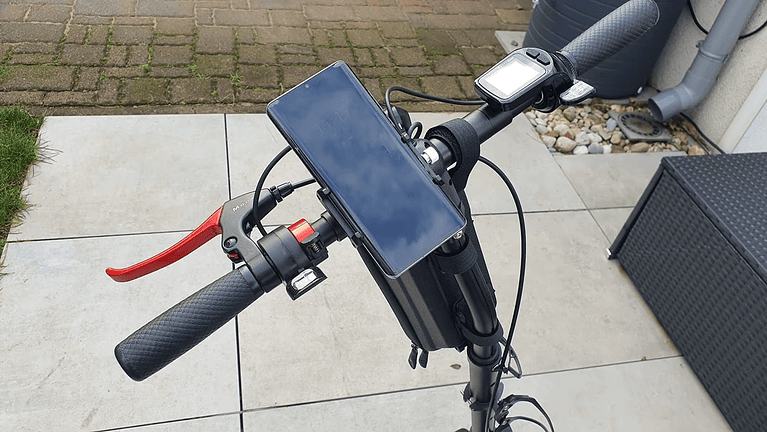 Lenker für Elektroroller mit stabiler E-Scooter-Handyhalterung, komplett mit Bremshebel und Digitalanzeige, ruht auf einer gefliesten Terrasse.