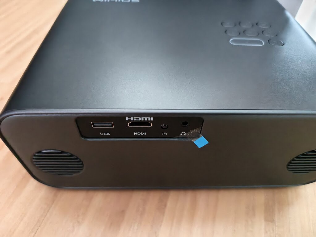 Eine Nahaufnahme der Rückseite eines schwarzen elektronischen Geräts, wie z. B. des WiMiUS G1 Test, mit USB-, HDMI-, IR- und Kopfhöreranschlüssen und einer blauen Lasche am IR-Anschluss.